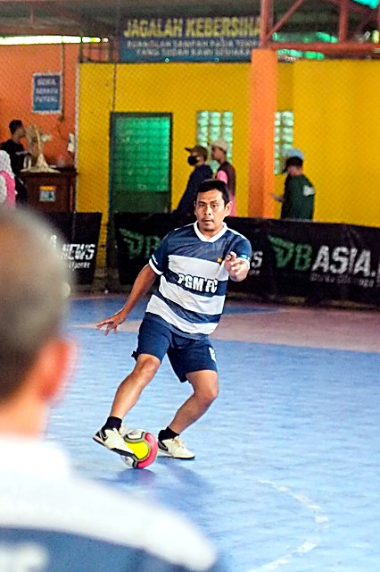 Pemain futsal menggiring bola di lapangan futsal Disen Arena